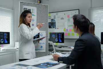 Obraz premium Asian businesswoman leading meeting and pointing at charts on board in office