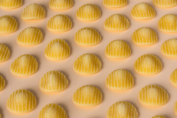 Background pasta . Side view of isolated a raw Italian durum wheat orecchiette pasta on a light orange background .