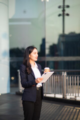 Fototapeta premium Young Asian businesswoman using a tablet on a bench in the city