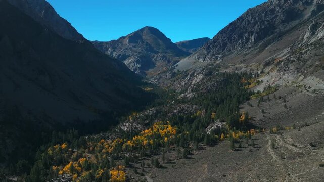 West Portal Entrance rugged Mountains Lee Vining Tioga Pass Road Yosemite National Park California aerial drone Ansel Adams Wilderness autumn fall yellow orange Aspen Trees blue skies backwards pan up