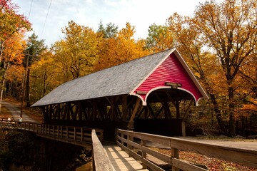 Red covered bridge at Flume Gorge State Park in New Hampshire during autumn.