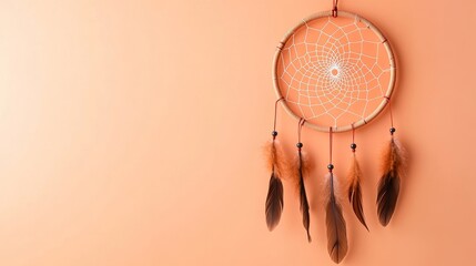 Obraz premium Dreamcatcher hanging against a soft peach backdrop, symbolizing protection and dreams