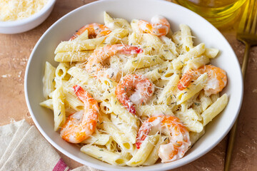 Penne pasta in creamy garlic sauce with shrimps and cheese. Italian food.