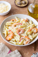 Penne pasta in creamy garlic sauce with shrimps and cheese. Italian food.