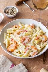 Penne pasta in creamy garlic sauce with shrimps and cheese. Italian food.