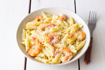 Penne pasta in creamy garlic sauce with shrimps and cheese. Italian food.