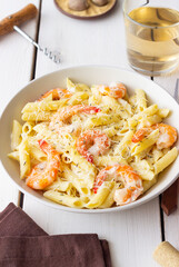 Penne pasta in creamy garlic sauce with shrimps and cheese. Italian food.