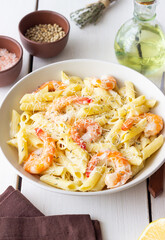 Penne pasta in creamy garlic sauce with shrimps and cheese. Italian food.