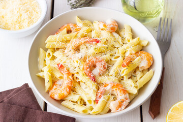 Penne pasta in creamy garlic sauce with shrimps and cheese. Italian food.