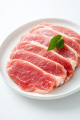 Slices of raw turkey brisket are artfully arranged on a white plate, showcasing their fresh, pinkish hue. A single green herb leaf adds a touch of color and vibrancy, emphasizing the quality