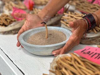 closeup of handmade incense sticks at street market outdoors with hands of a seller holding plate...