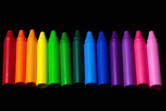 row of crayons lined up against a black background