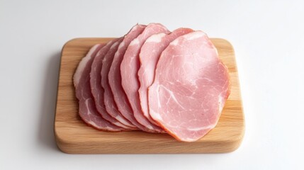 A plate of deli-style sliced ham arranged neatly on a wooden cutting board,