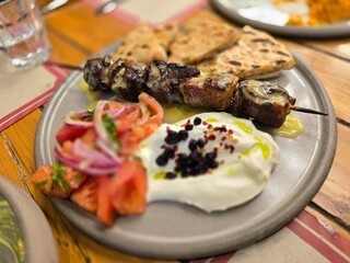 Delicious grilled kebab served with fresh salad and flatbread on a rustic wooden table
