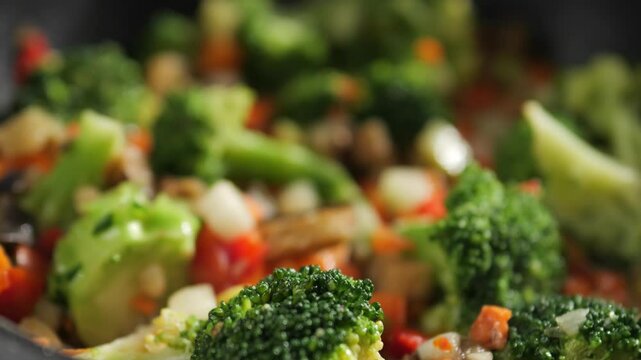 Defrosted vegetable stew is cooked in a frying pan. A vegetarian dish made with chopped vegetables and broccoli.