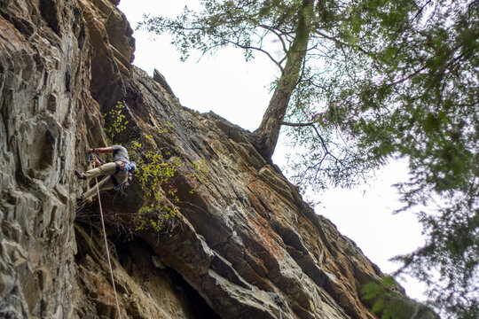 A rock climber descends from rocky cliff face using gear and ropes