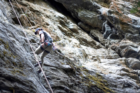 A climber descends from rock face using gear and ropes