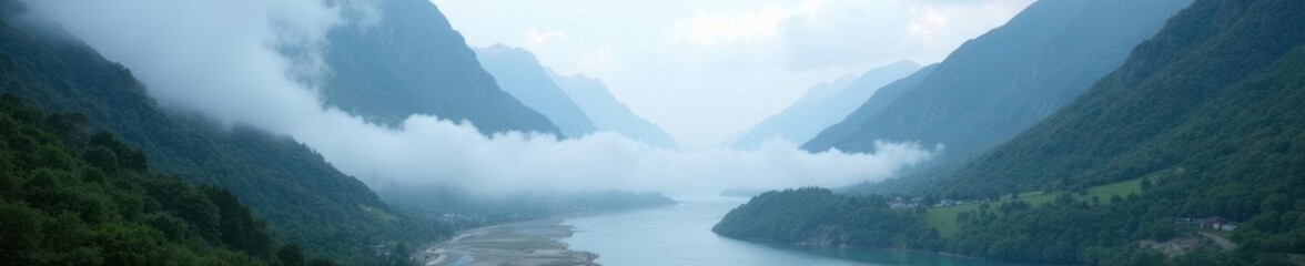 Obraz premium Fog shrouds the valley and river amidst towering mountains, mountains, misty