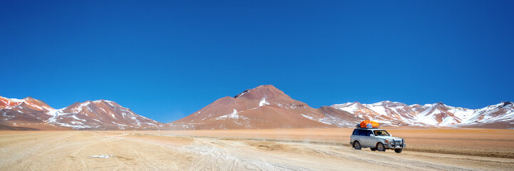 4x4 car on a gravel road in Sud Lipez Bolivia, panoramic landscape, adventure travel web banner © Delphotostock