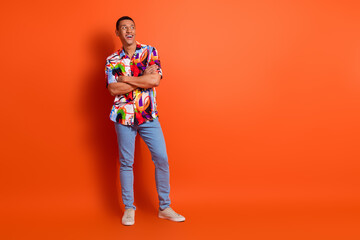 Fototapeta premium Young man in vibrant shirt stands confidently against a vivid orange background, embodying youthful flair and contemporary style