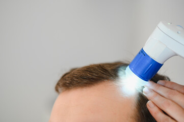 A trichologist examines the hair of a man who begins alopecia. Consultation with a dermatologist....