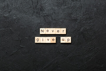 never give up word written on wood block. never give up text on cement table for your desing,...