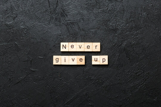 never give up word written on wood block. never give up text on cement table for your desing, concept
