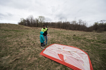 Building a colorful kite together in a serene field on a cloudy afternoon while enjoying the bond between parent and child