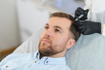 Side view of handsome man getting hair treatment at beauty salon. Man having mesotherapy session at...