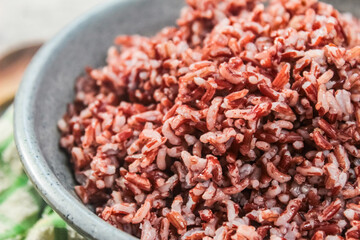 close-up of a bowl of cooked brown rice on a table with a spoon and fork