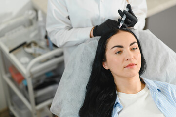 Beautiful middle woman receiving hair mesotherapy injection from competent beautician