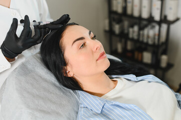 Young woman with hair problem receiving injection in clinic. Hair renewal rejuvenation pampering...