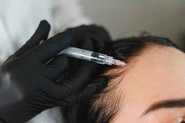 Lady receiving hair mesotherapy injections from professional trichologist. Hair treatment in...