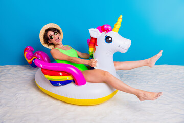 Young woman enjoying summer vibes with a unicorn pool float on sand © deagreez