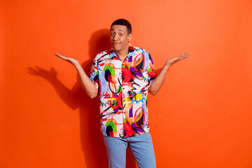 Photo portrait of pretty young male shrug shoulders wear trendy colorful outfit isolated on orange...