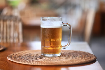 A mug of cold beer in a bar with a blurred background