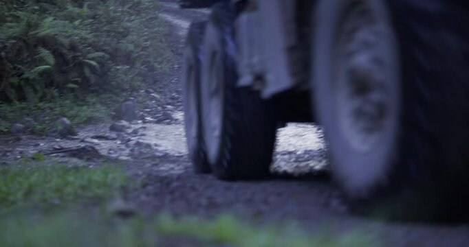 Large WW2 truck driving through muddy road puddle - low, steady cam shot
