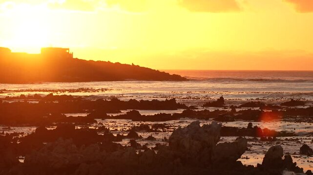 Sunset over False Bay near the village of Pringle Bay, with vibrant sky reflections on the tranquil water, creating a serene and picturesque coastal scene