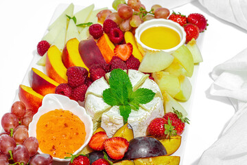 Assorted cheese plate with fruits and sauces isolated on white background. Vegan snacks concept