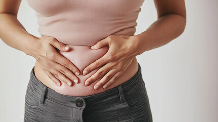 Close up of woman pinching belly fat with hands on white background: weight loss motivation, body awareness and health concept