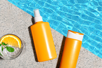 Sunscreen products and cocktail drink near pool water