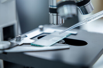 Close up of a microscope with a test glass under the lens