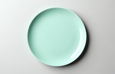 Top view of isolated empty round cyan plate. Dish with space for design, logo or text. Light gray background ceramic tableware, porcelain crockery. Kitchen blank for food, lunch, dinner preparation.