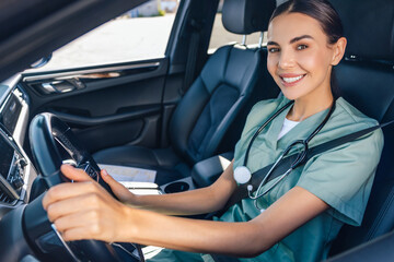 Smiling female doctor sitting in the car on a drivers seat