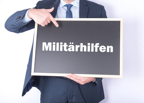 Politiker mit einem Schild auf dem Milit&auml;rhilfen steht