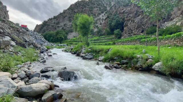 Flowing river winding through lush terraced fields in Naran Valley, a scenic tourist destination in Khyber Pakhtunkhwa, Pakistan, showcasing stunning natural beauty