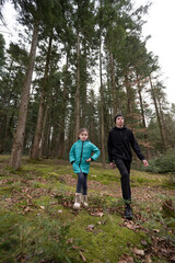 Exploring the vibrant forest trails, a child and an adult wander through lush greenery, enjoying...