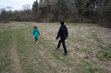 Exploring nature trails together on a cool spring day with family along a winding path surrounded by tall trees and soft grass