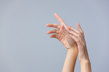 A Captivating Close-Up of Elegantly Arched Hands Against a Soft Gray Background, Highlighting Grace...