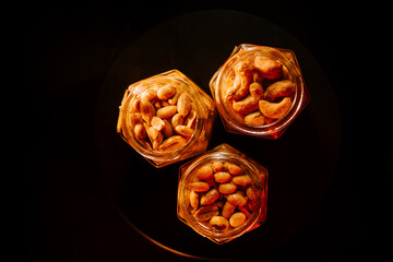 Jars filled with roasted nuts on a dark surface showcasing variety and texture in dim lighting